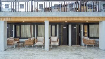 Een hotel lobby met een overdekte zithoek, meerdere deuren en een balkon met leuningen.