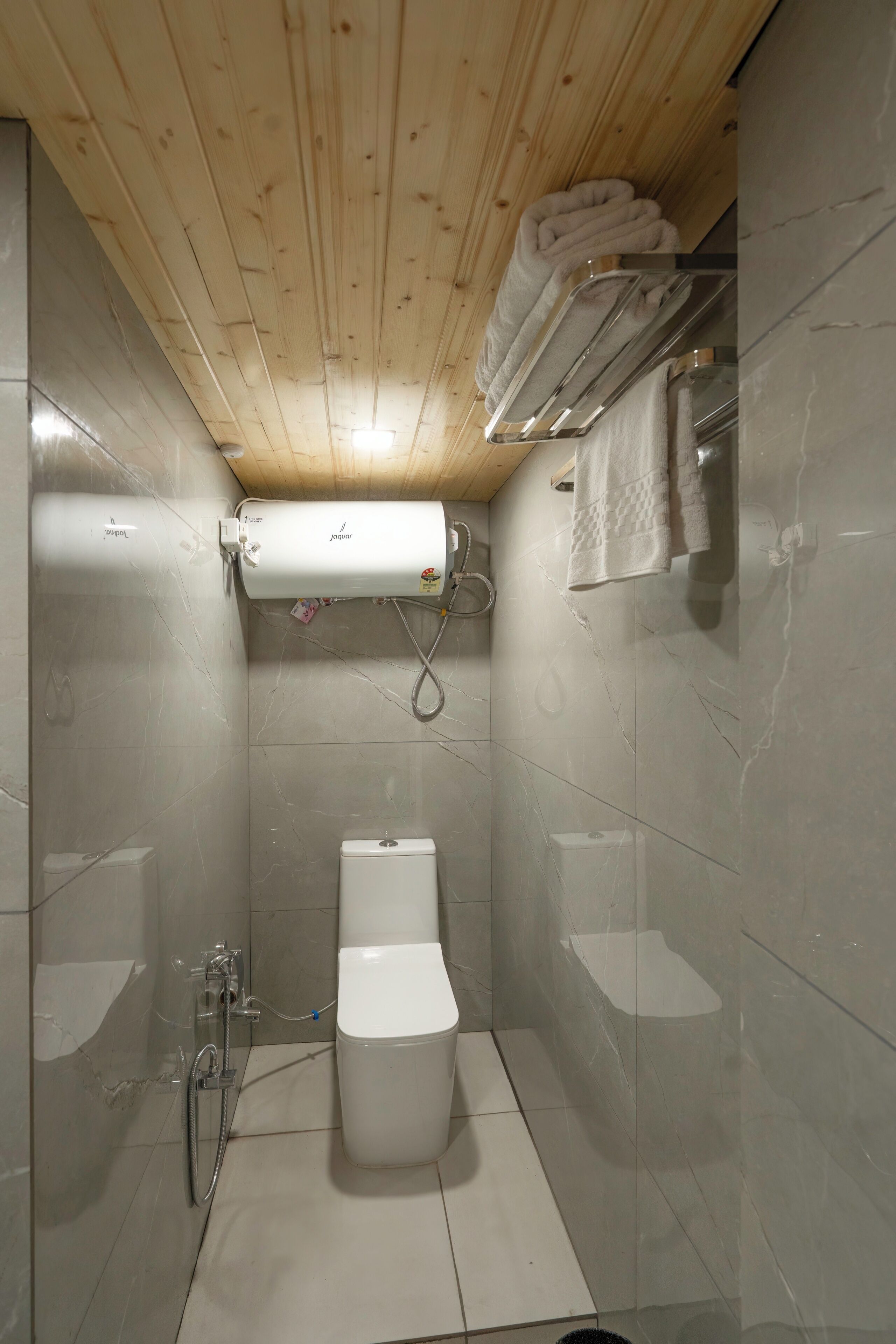 Un baño pequeño y funcional con inodoro, ducha y barra para toallas.