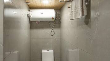 Un baño pequeño y funcional con inodoro, ducha y barra para toallas.
