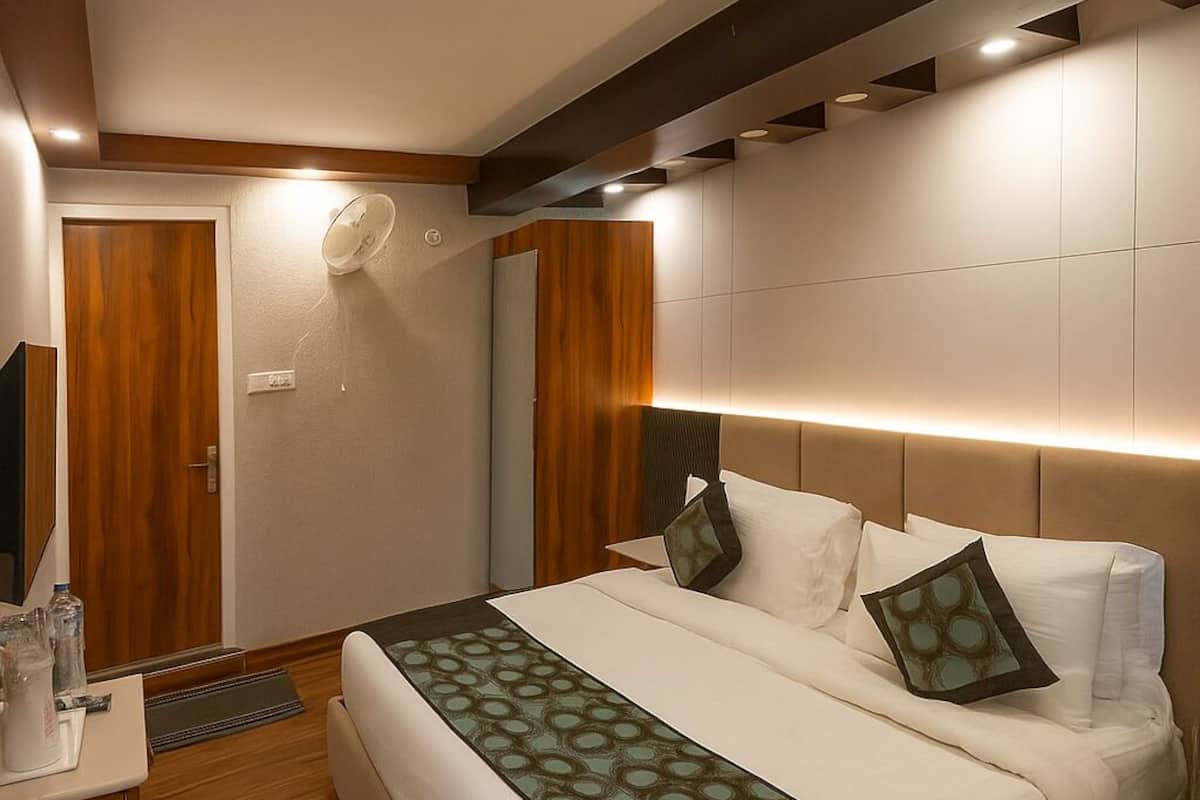 Ein modernes Hotelzimmer mit einem großen Bett, Holzboden, einem Nachttisch und einem an der Wand befestigten Fernseher.