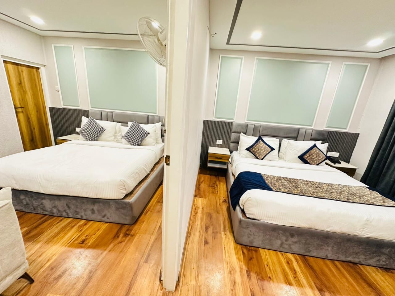 A hotel room with two beds, wooden flooring, and a modern design.
