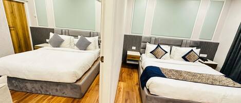 A hotel room with two beds, wooden flooring, and a modern design.