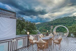 A terrace with wicker furniture, a view of a lake, and a sign reading 'NAINITAL'. - Excel Hotels & Resorts Mall Road Nainital (Nainital)