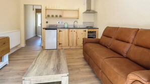 Ein kompakter Wohnbereich mit einer Küchenzeile, einem Sofa und einem Holztisch.