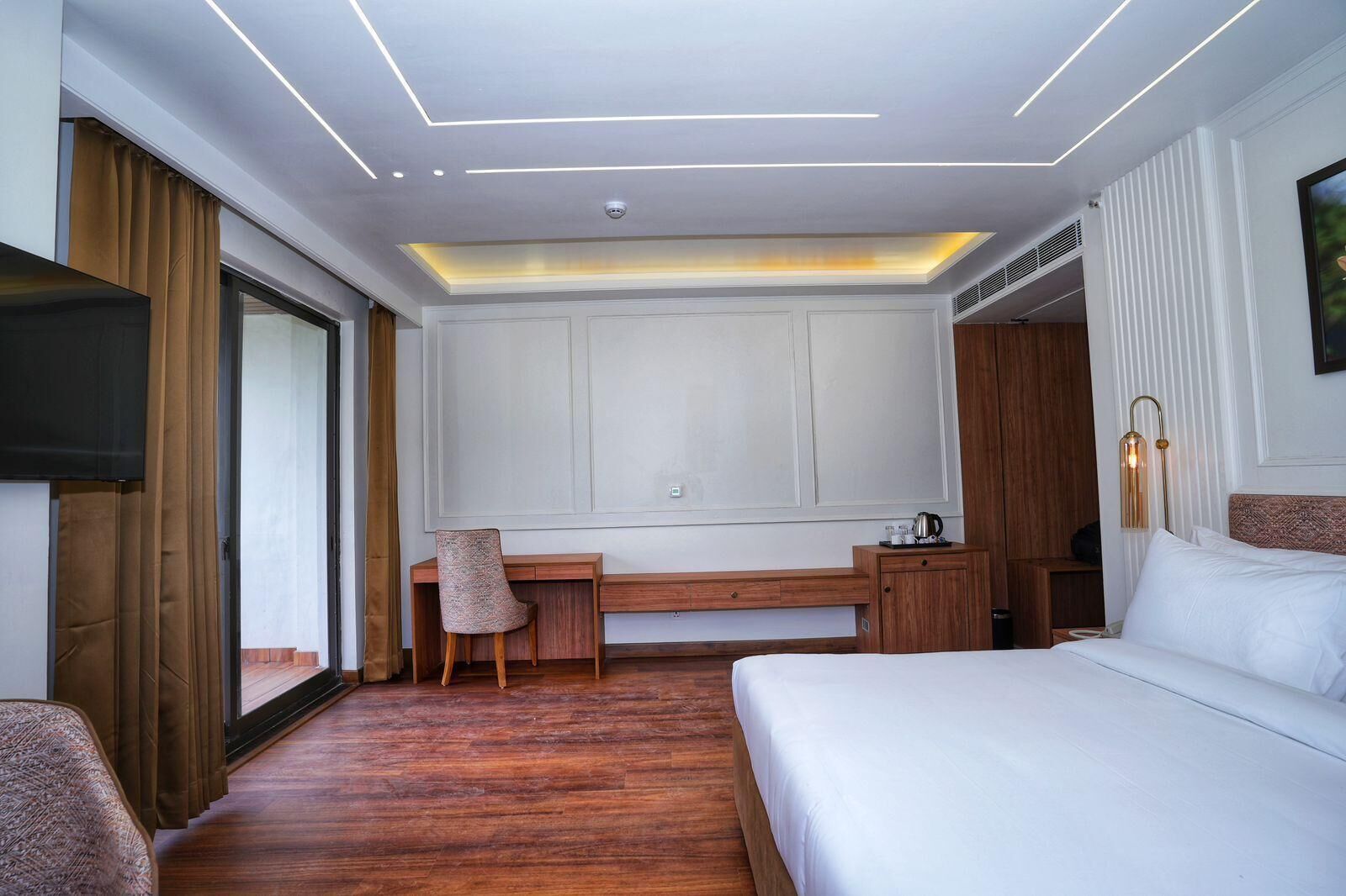 Una habitación de hotel con cama, escritorio, silla, televisión y armario.
