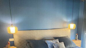 A bedroom with a bed, two bedside tables, and two wall-mounted lamps.