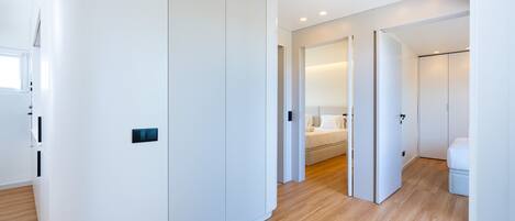 A modern hotel room with a wooden floor, white walls, and a large wardrobe.