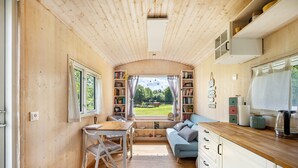 Een houten interieur met een eethoek, bank, keukenblad en uitzicht door een raam.