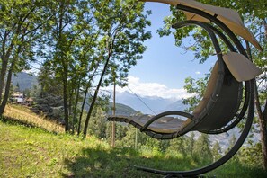 Un hamac installé dans un cadre naturel, avec des arbres et des montagnes en arrière-plan.