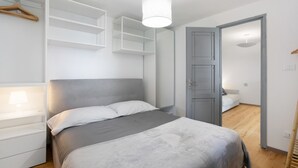 A bedroom with a bed, a wardrobe, and a hanging space. - 'Coin Vert' Apartment with Mountain Views, Shared Garden and Wi-Fi (Gressan)