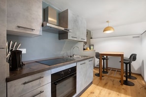 A modern kitchen with a built-in oven, a sink, and a wooden dining table with two chairs.