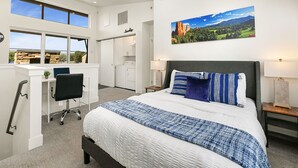 Ein modernes Schlafzimmer mit einem großen Bett, einem Schreibtisch und Blick auf eine Berglandschaft.