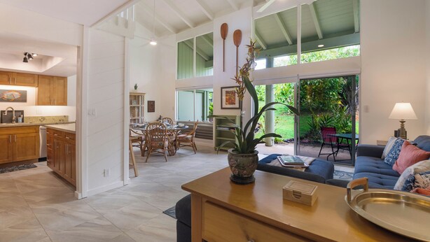 A spacious living area with a large dining table, a sofa, and a kitchen area with wooden cabinets.