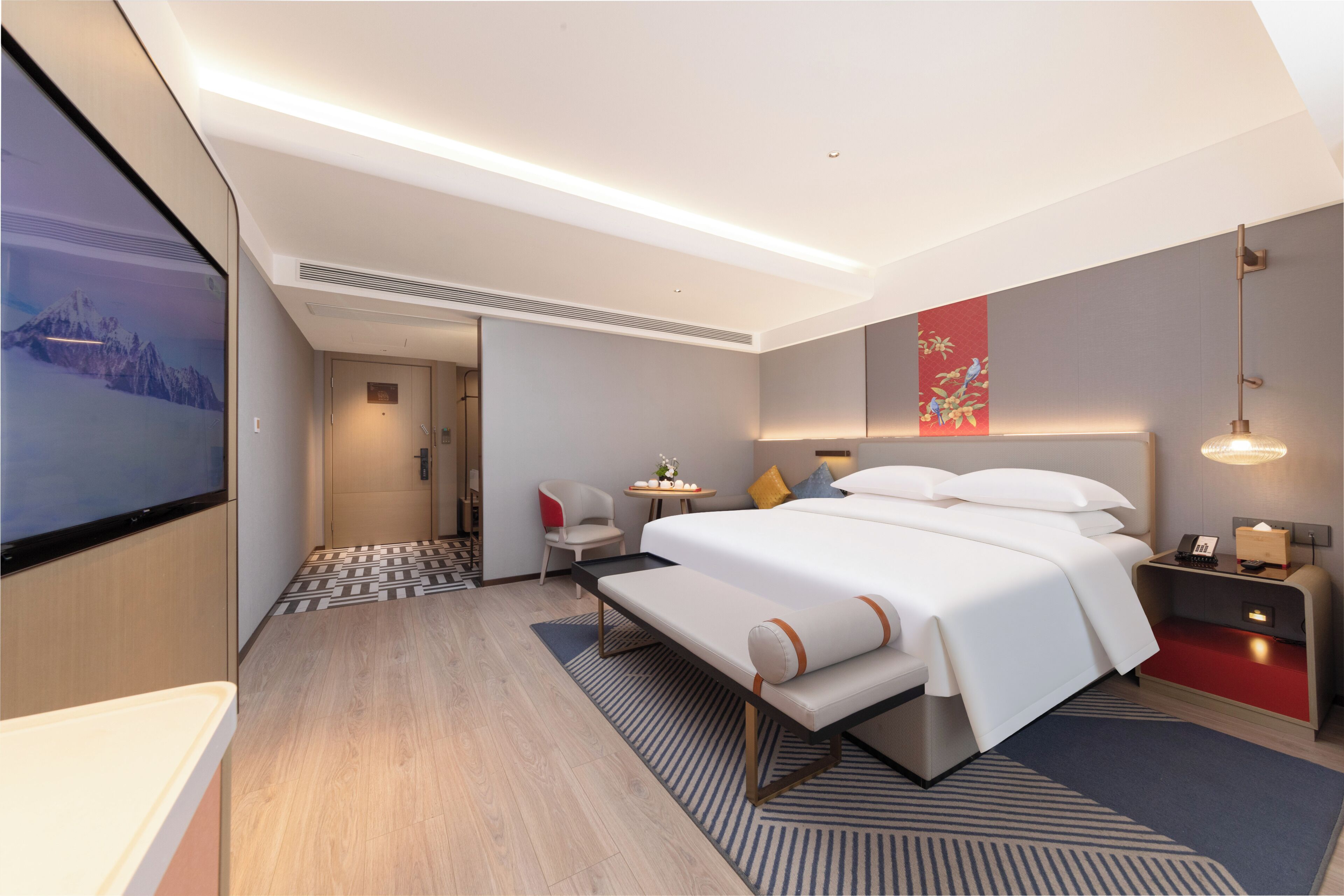 Een moderne hotelkamer met een groot bed, nachtkastjes, een bureau en een televisie.