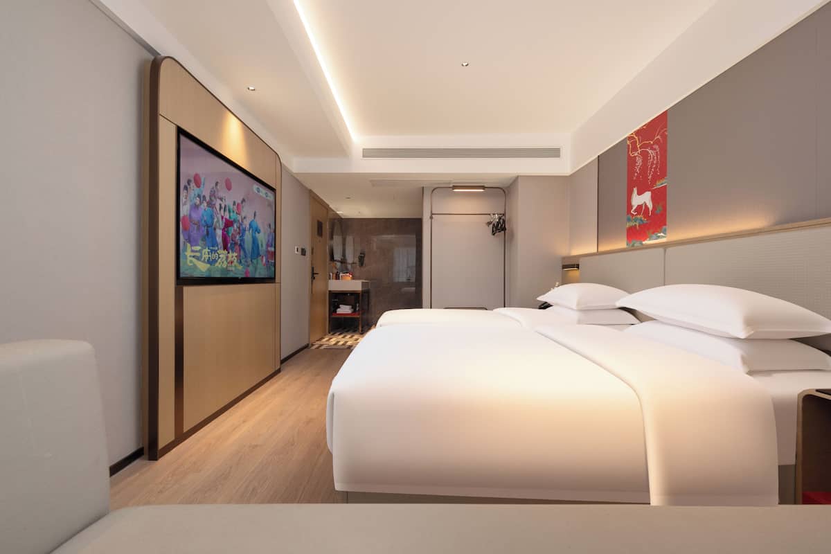 A modern hotel room with a large bed, a desk, and a bathroom.