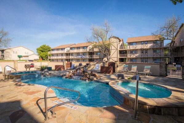 Ein Hotelpoolbereich mit Whirlpool, Liegestühlen und einer Terrassenanlage aus Stein.