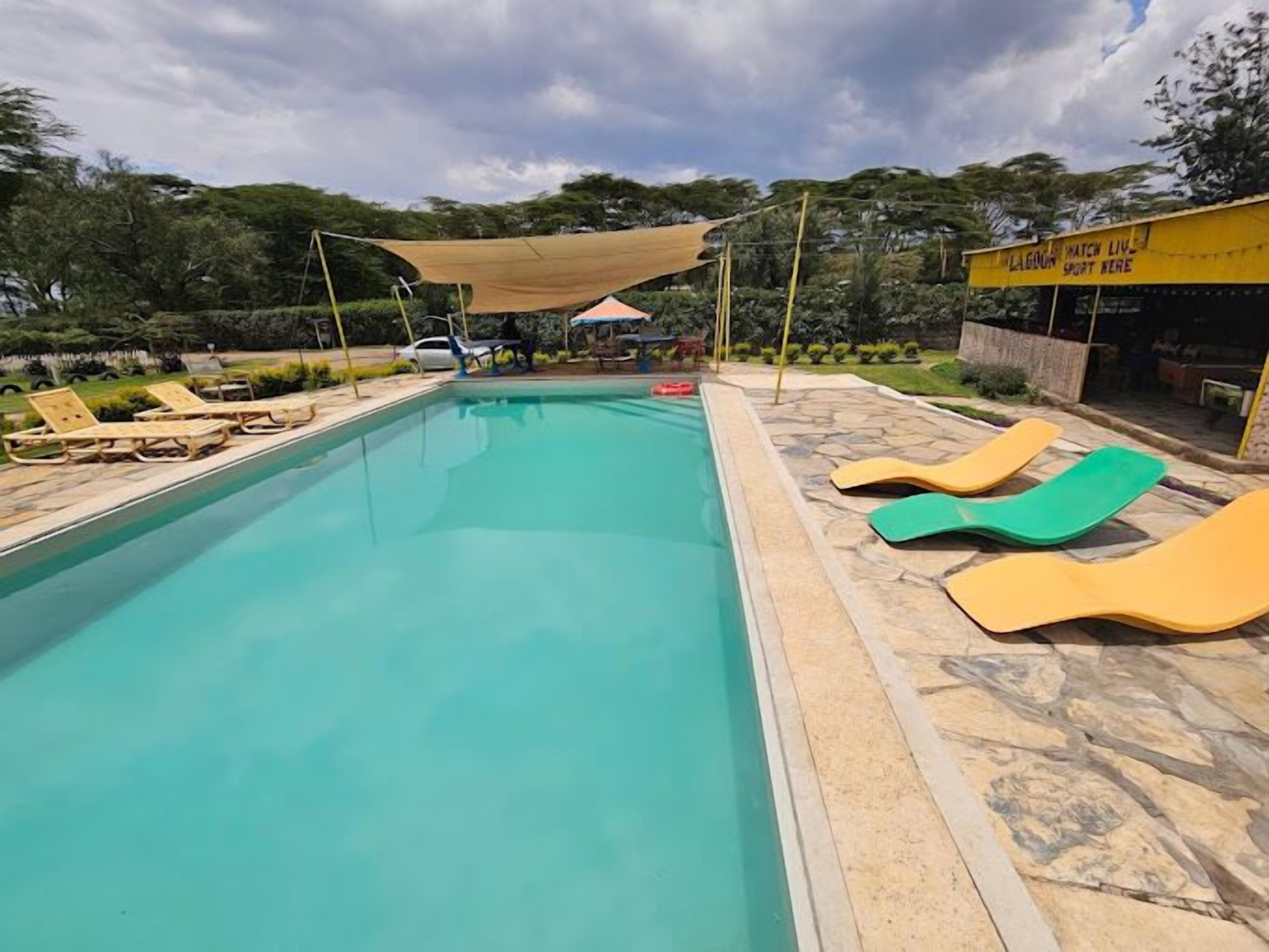 A swimming pool with lounge chairs and a shaded area.