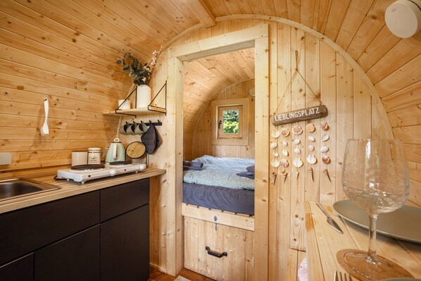 A compact wooden cabin with a kitchenette, a bed, and a dining area.