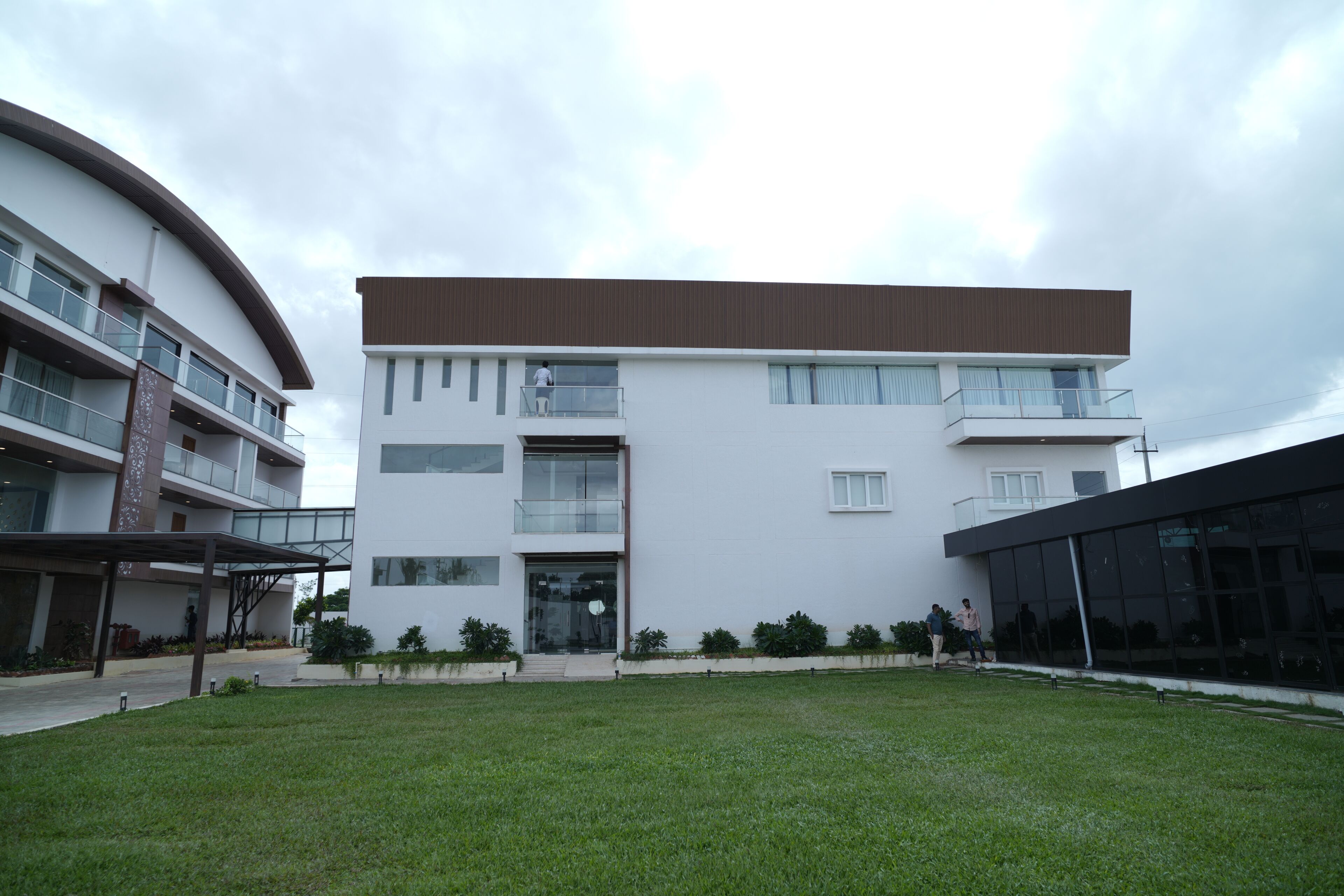 A modern multi-story building with a flat roof, large windows, and a covered entrance area.