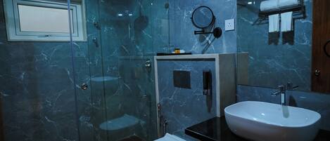 Une salle de bain avec une douche à parois de verre, des toilettes blanches, un lavabo et un miroir.