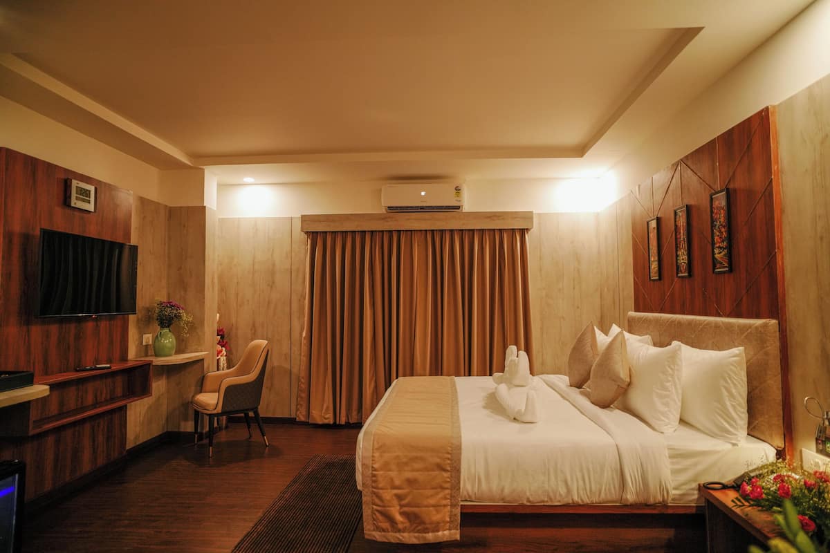 A hotel room with a bed, a TV, a desk, and a chair.