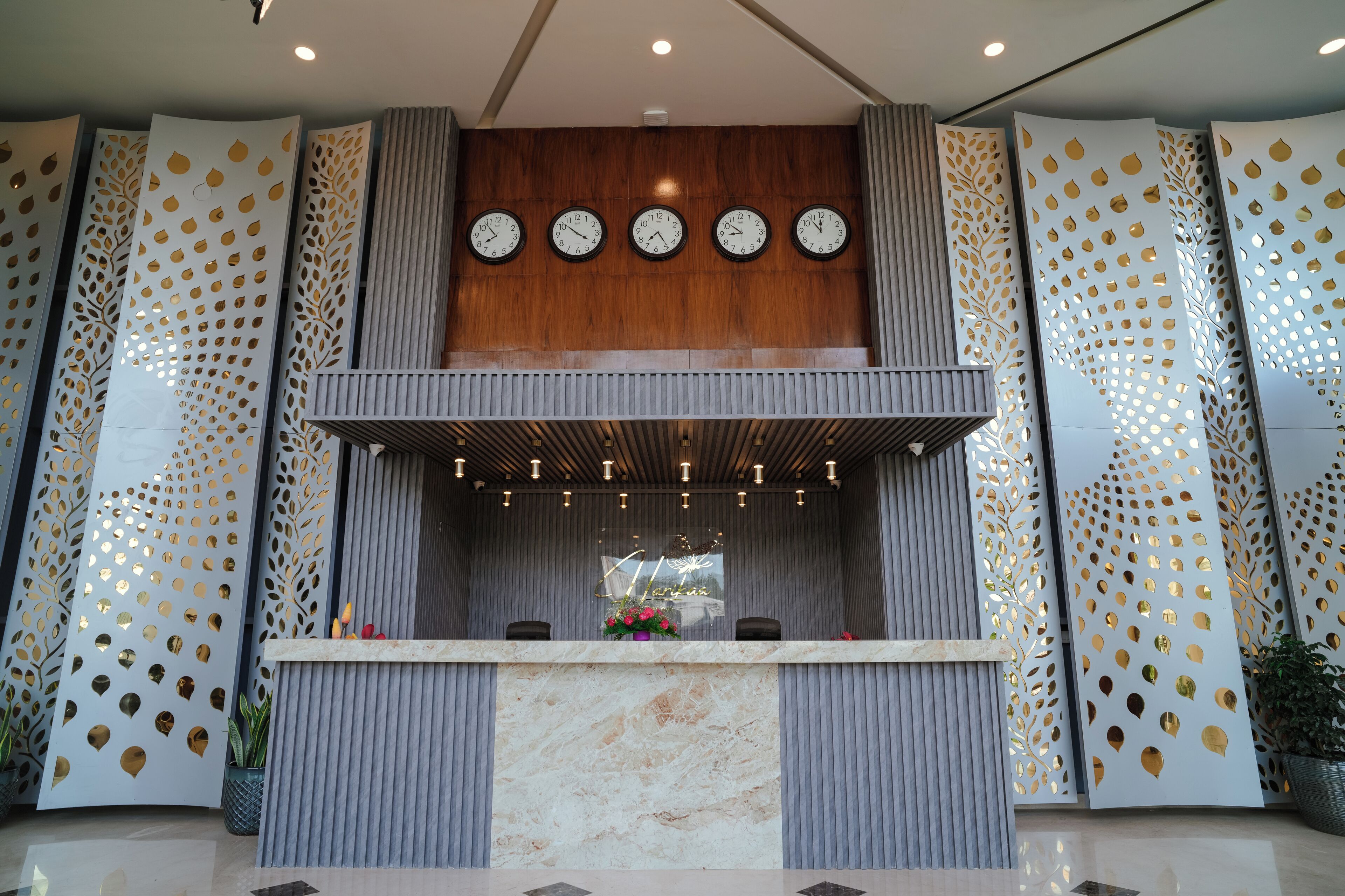 A reception area with a marble counter, wooden paneling, and decorative perforated panels.