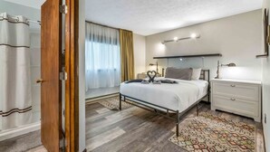 A bedroom with a bed, bedside table, and a window with curtains.