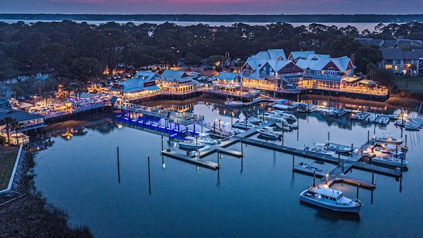 A waterfront property with multiple docked boats, a pier, and buildings with outdoor seating areas. - Sea Pines Townhome | Walk to Harbour Town, Pool & Bike Trails (Hilton Head Island)