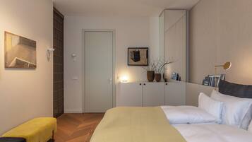 A modern bedroom with a bed, bedside tables, a bench, and a door.