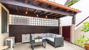 Eine Terrasse im Freien mit einer Couch, einem Tisch und einem Blumentopf.