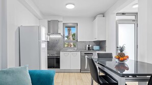 Een moderne keuken met witte kasten, een roestvrijstalen koelkast en een glazen eettafel.
