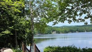 A patio with wicker chairs and a table overlooking a lake.