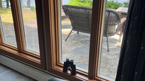 A room with a large window overlooking a lake and greenery.