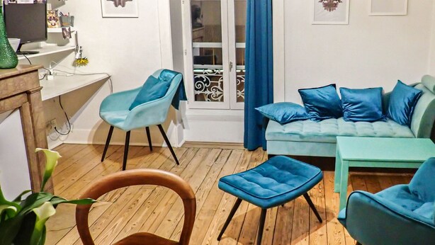 Un salon avec un canapé, des fauteuils, une table et une bibliothèque.
