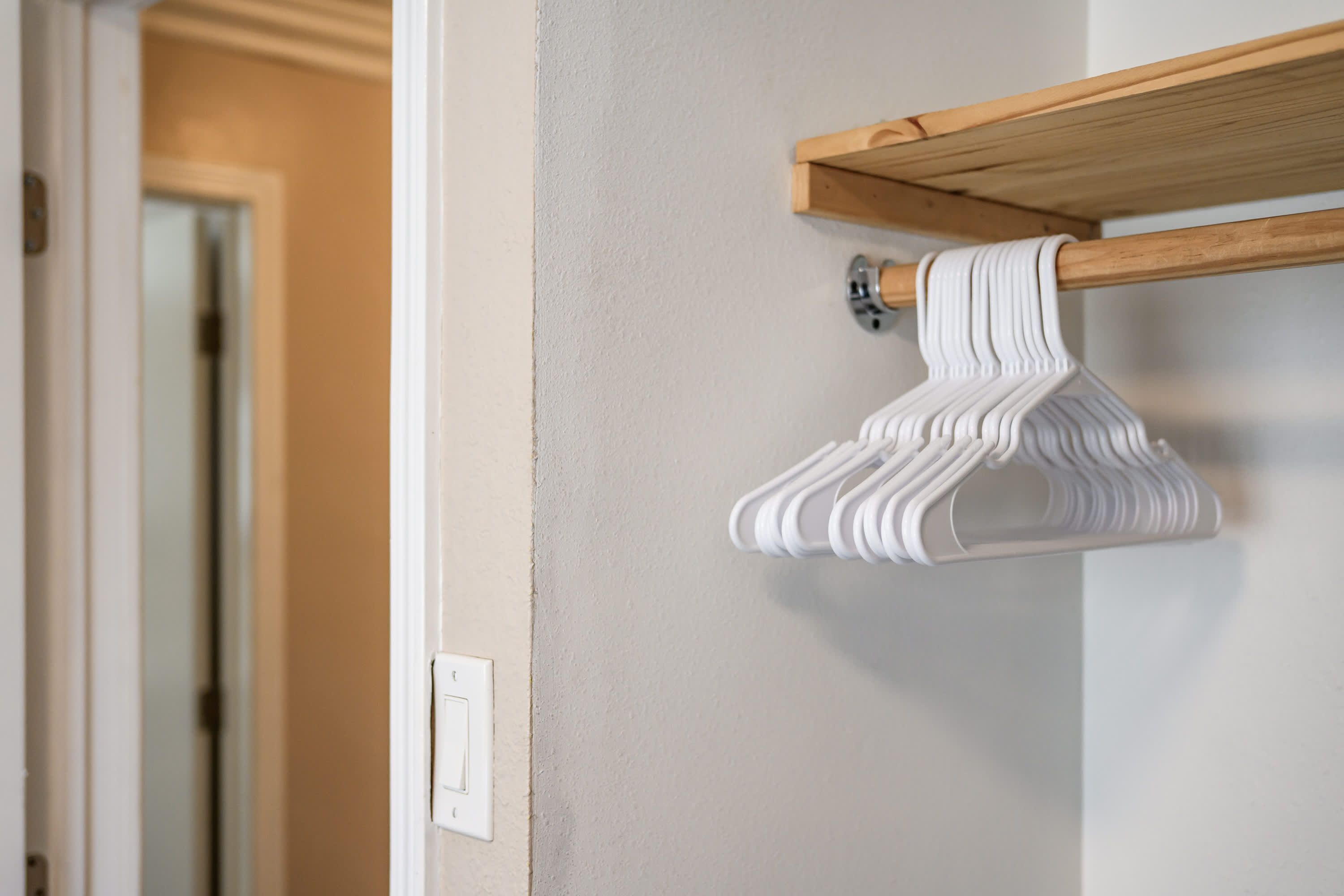 A wooden shelf with a white hanging garment rack against a wall.