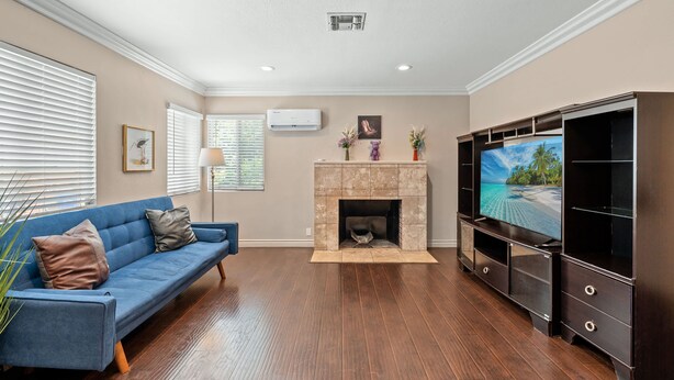 A living room with a blue sofa, a fireplace, a TV, and wooden flooring.