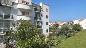 Un edifici residencial de diversos pisos amb balcons, un jardí ben cuidat i una vista clara del barri circumdant.