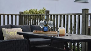 A wicker outdoor seating area with a table, two wine glasses, a bottle of wine, and a tray with a bottle and a glass of lemonade. - Ty Llaeth 2-bed Cottage, Sleeps 4, Pet Friendly (Carmarthen)