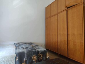 Una habitación con cama, armario y una pequeña mesa.