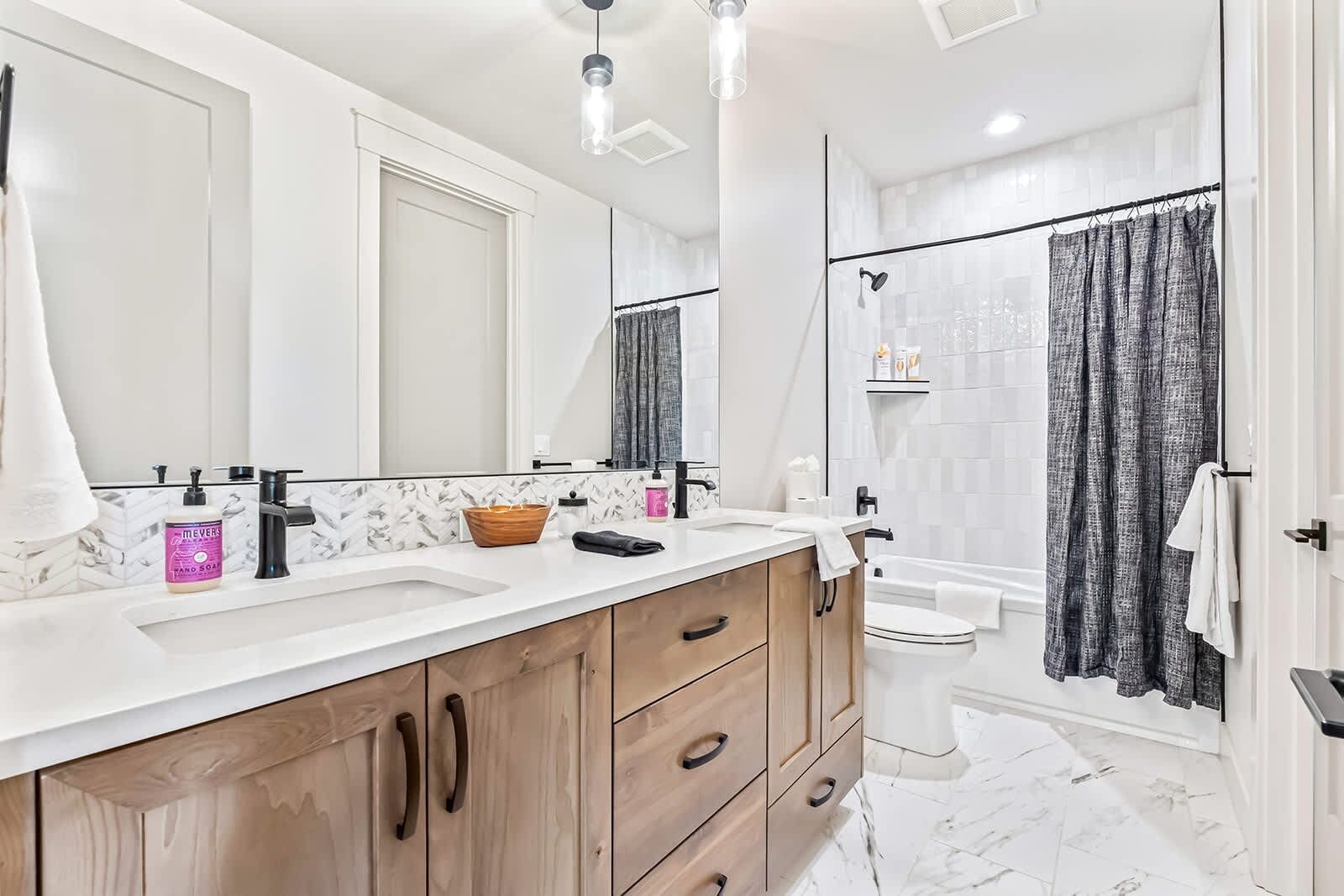 Une salle de bain moderne avec un meuble-lavabo à deux vasques, une douche avec une porte en verre et un sol carrelé en marbre.