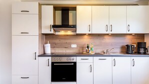 A modern kitchen with white cabinets, a black oven, and a stainless steel range hood. - Apartment 'Mayerhofer 1' with Private Terrace, Shared Garden and Wi-Fi (Arnstorf)