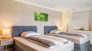 A hotel room with two beds, a nightstand with a lamp, a wall-mounted picture, and a radiator. - Apartment 'Mayerhofer 1' with Private Terrace, Shared Garden and Wi-Fi (Arnstorf)