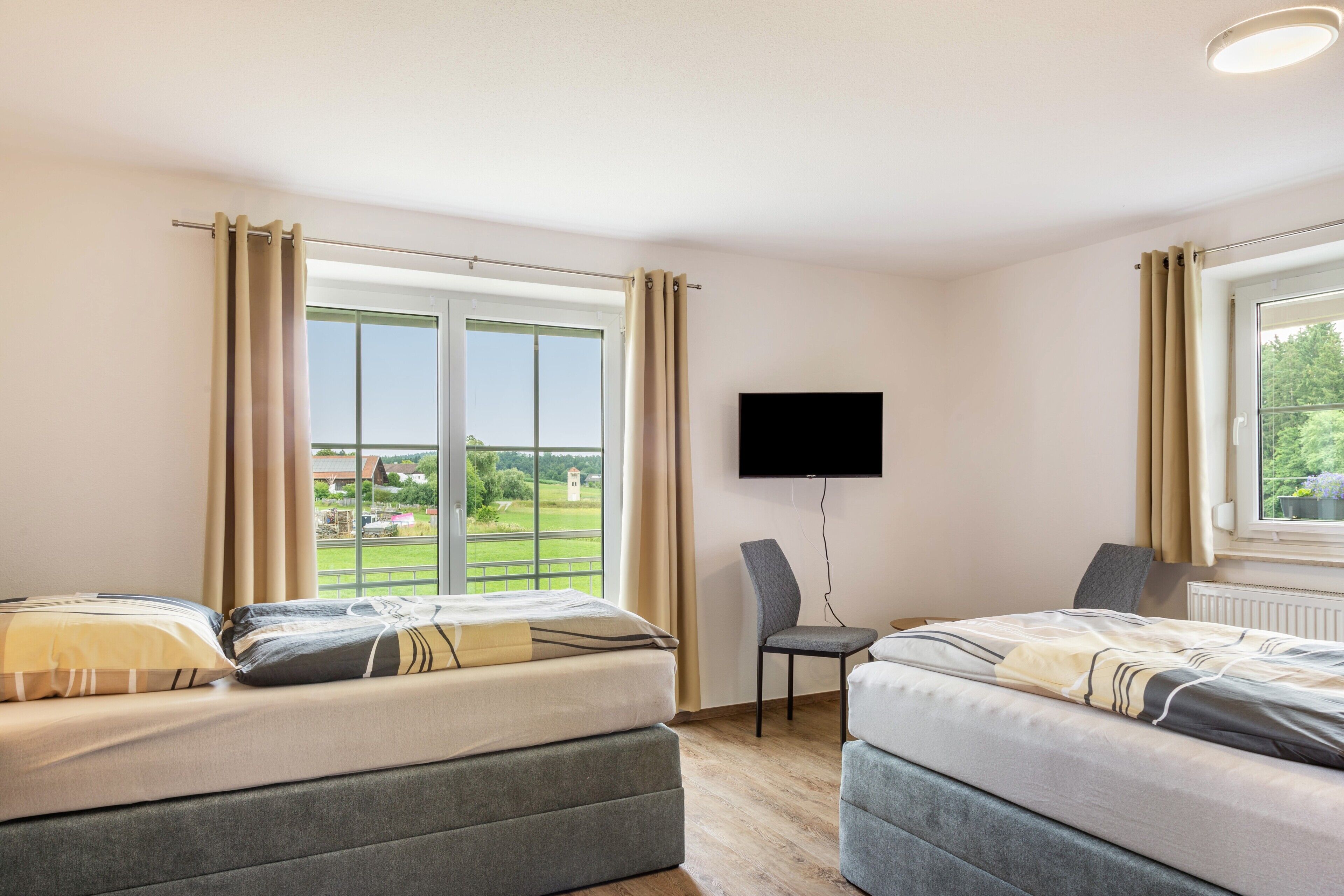 Camera d'albergo con due letti, televisione e vista sull'esterno.