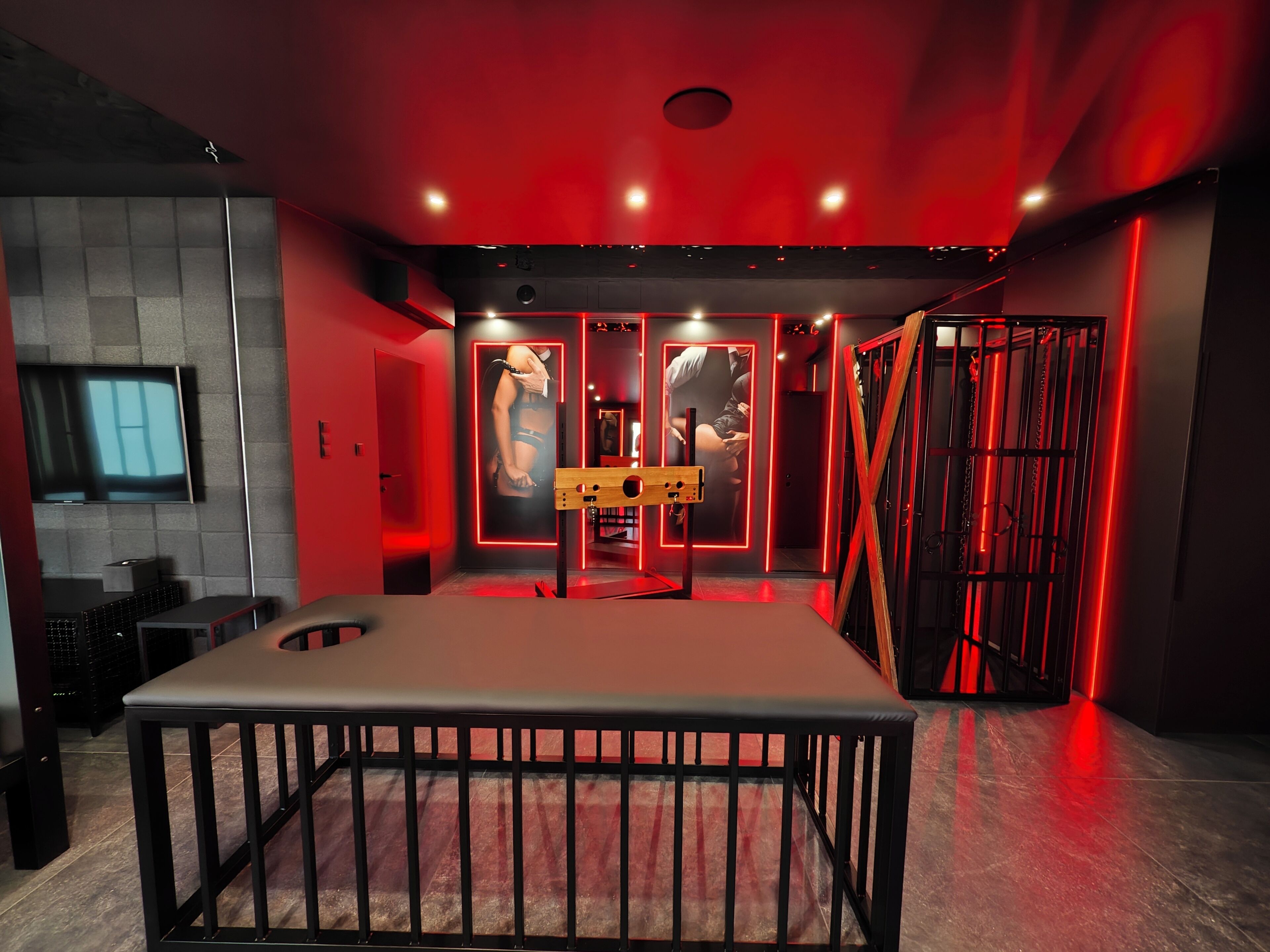 A modern interior with a central table, red lighting, and a television on the left.