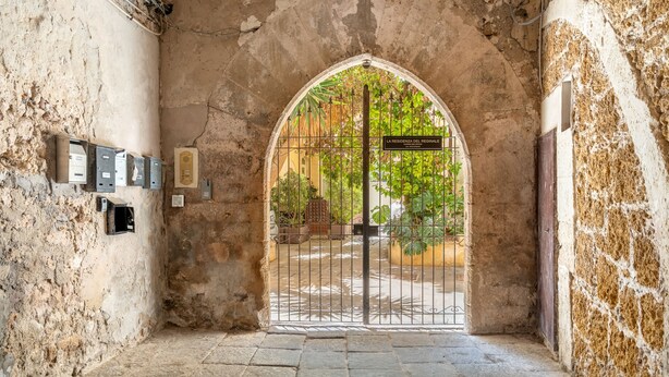 An arched doorway with a metal gate, a sign reading "LA RESIDENZA DEL REGINALE," and a stone floor. - La Casa di Nonna Anna by Wonderful Italy (Syracuse)