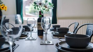 Una mesa de comedor con copas de vino, una botella y cuencos negros.