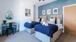Un dormitorio con dos camas, un escritorio, una silla y un espejo.