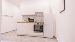 Eine kleine Küche mit weißen Schränken, einer Mikrowelle, einem Backofen und einem Kühlschrank.