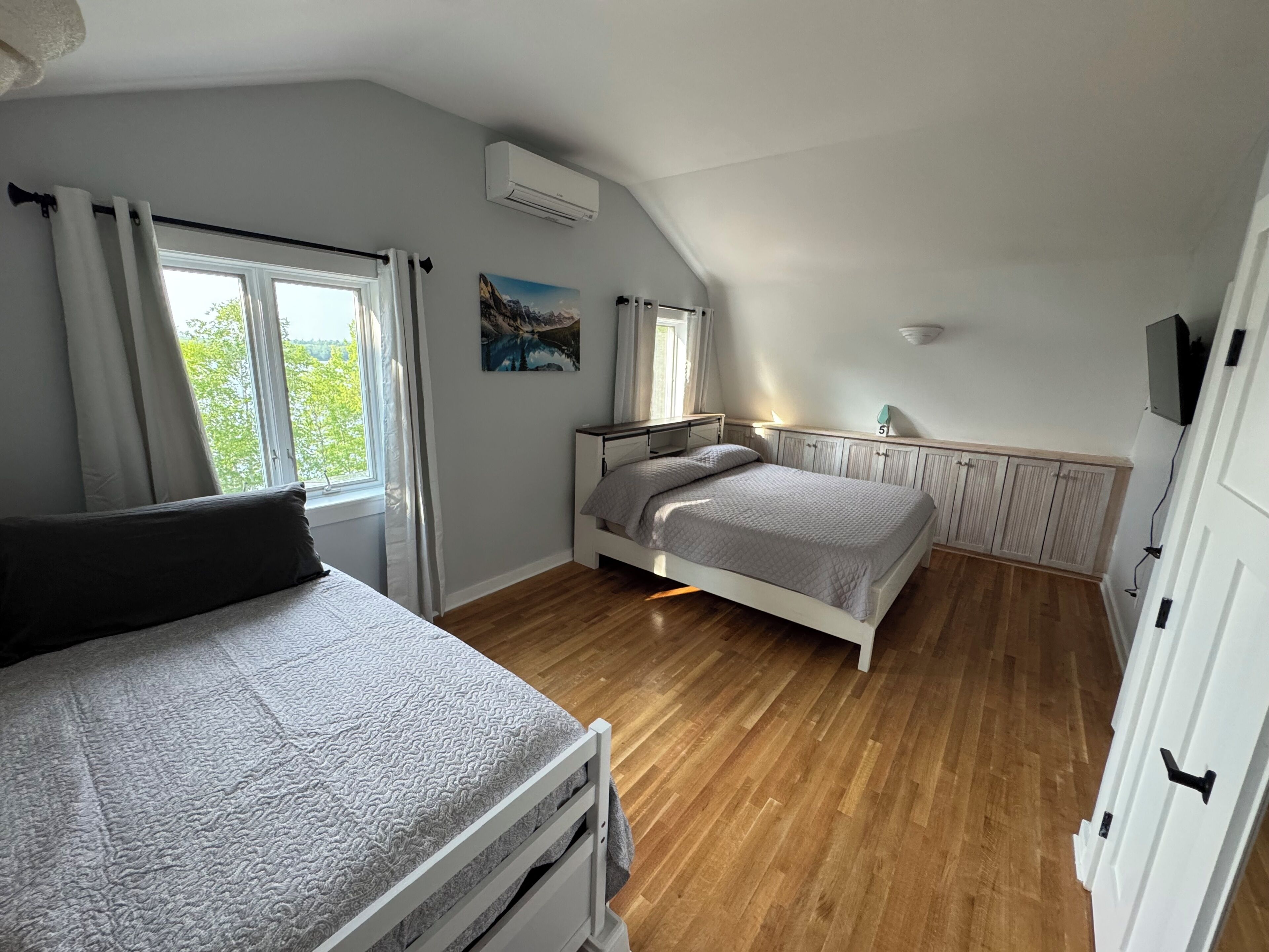 Ein Schlafzimmer mit Bett, Fenster, Heizkörper und einem Bild an der Wand.