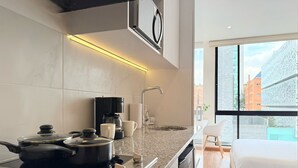 A modern kitchen with a built-in stove, coffee maker, and a large window offering a city view. - KD Otoño by Weeki (Bogotá)
